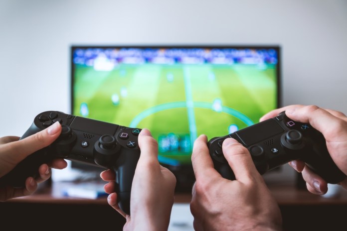 Two men play FIFA game on PlayStation