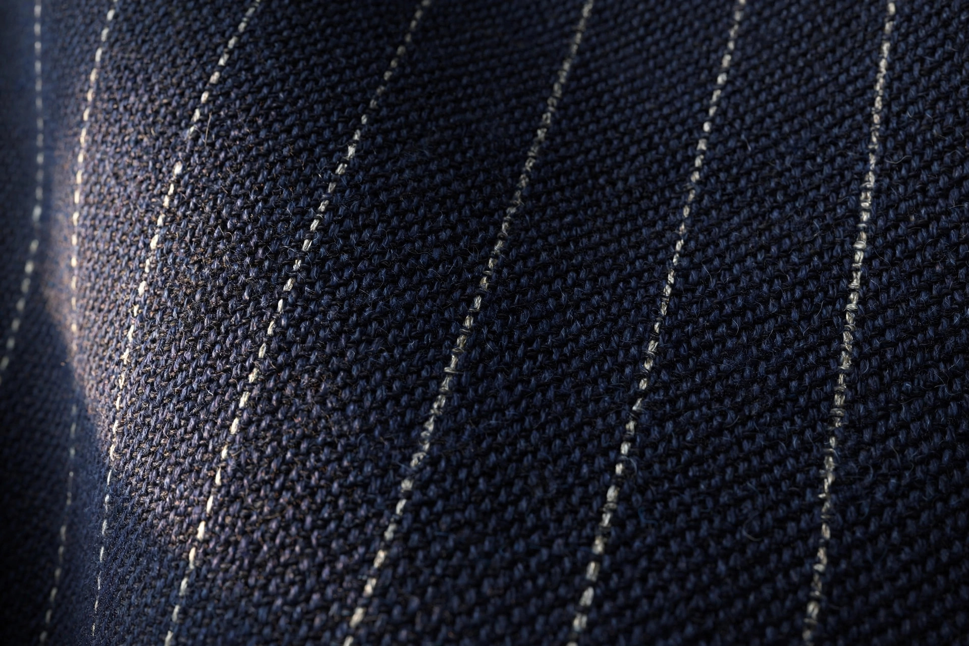 Close-up of navy wool fabric woven with fine pale pinstripes